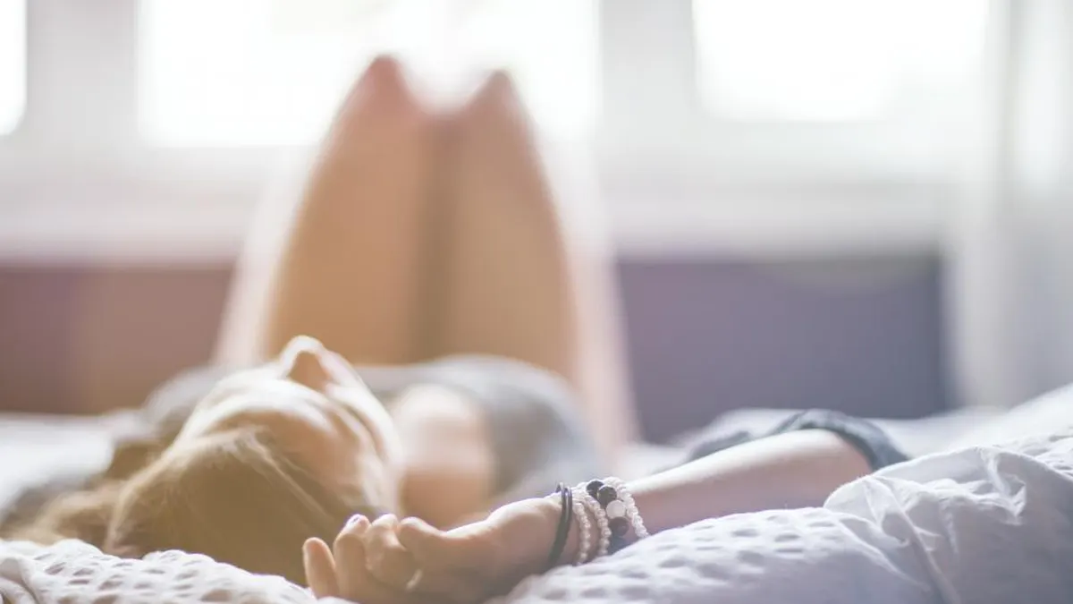 Erschöpfte Frau liegt mit geschlossenen Augen im Bett