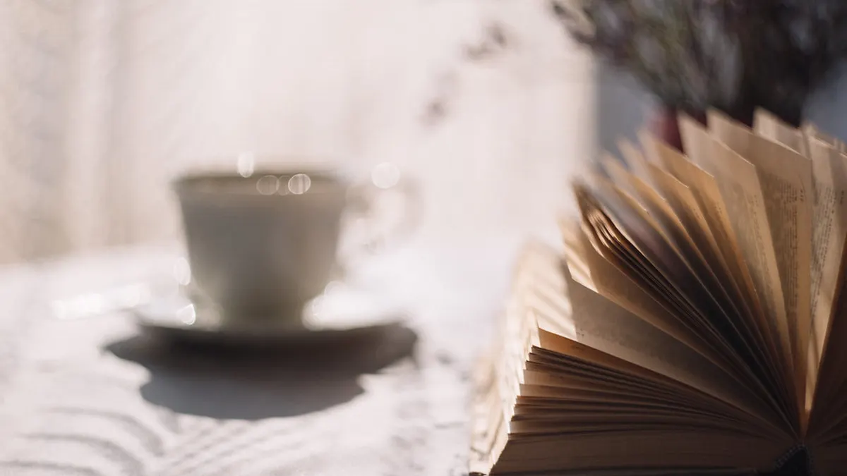 Tasse Tee und Buch auf einem gemütlichen Sofa